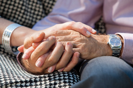 Couple holding hands on lap in parkの写真素材