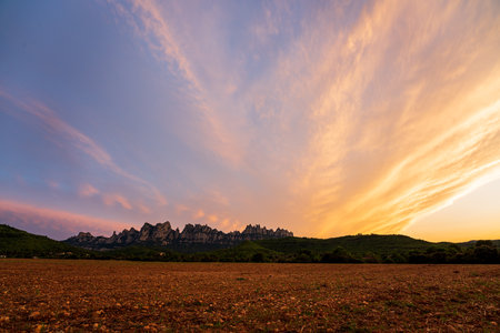 Sunset on the mountain of Montserrat, the most famous mountain in Catalonia. Clouds in the sky completely orange.の写真素材
