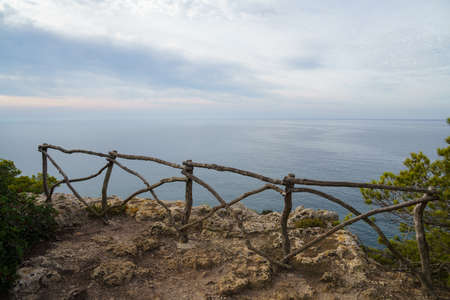 Cala Macarelleta, Menorca. September 2021. Paradise beach on the island of Menorca. Perfect place to relax and enjoy nature in summer. Wooden fence on the coastal path.の写真素材