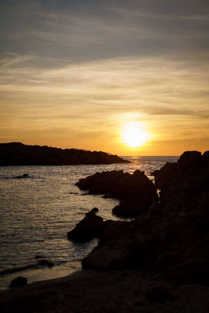 Cala Viola de Ponent, Menorca. September 2021. Magnificent sunset in the Mediterranean Sea. On one of the paradisaical beaches of the island of Menorca.の写真素材