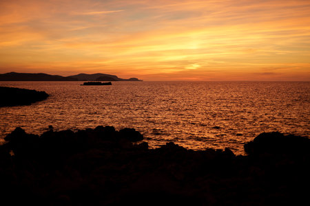 Cala Viola de Ponent, Menorca. September 2021. Magnificent sunset in the Mediterranean Sea. On one of the paradisaical beaches of the island of Menorca.の写真素材