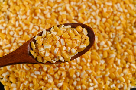 Cereal in wooden spoon on a background of yellow corn.