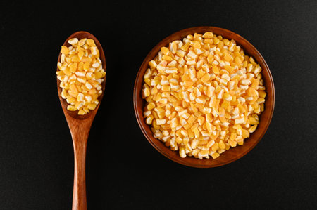 Corn seeds in wooden bowl and spoon on black background, top viewの写真素材