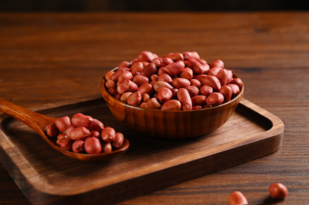 Peanuts in wooden bowl and spoon on wooden table, closeupの写真素材