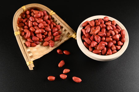 Raw peanuts in a bowl and in a basket on a black background