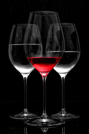Three wineglasses two with water one with red wine on a black table with a black background. Cocktail bar food concept.の写真素材