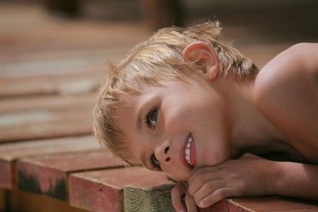 smiling boy lying on wood planksの写真素材