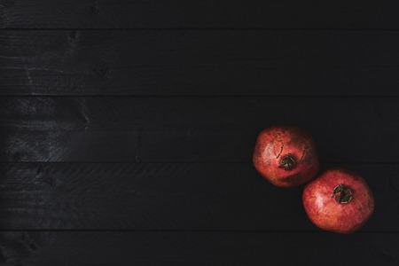 Flat lay of ripe pomegranate fruit on black wooden vintage background. Top view with copy space.の写真素材