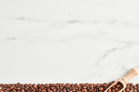 Coffee beans and wooden scoop on marble background with copy space. Flat layの写真素材