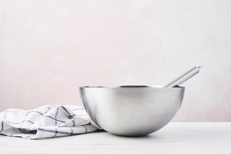 Baking concept. Bowl with a whisk and dishcloth on white marble table over pink background with copy space.の写真素材
