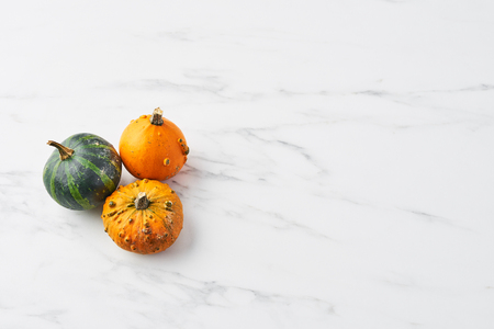 Top view of yellow, green and orange pumpkin on white marble table. Selective focus, copy space.の写真素材