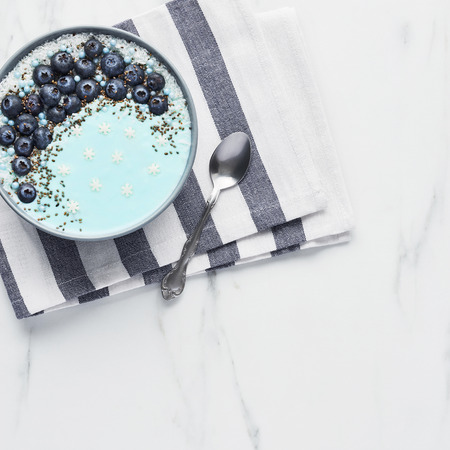 Top view of blue yogurt smoothie bowl made with blueberry, coconut flour, chia seeds and sugar...