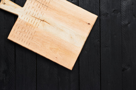 Top view of new handmade chopping board on black wooden table with copy space.の写真素材