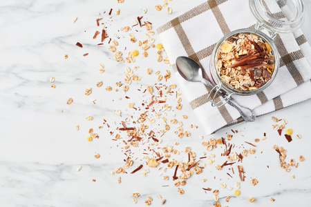 Top view of healthy breakfast. Jar of healthy yogurt with strawberry sauce, oat and chocolate on white marble table. Close up with copy space.の写真素材