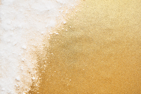 White powdery snow on golden glitter background. Snow and glitter for winter and Christmas gift concept design. Abstract white and gold background.の写真素材