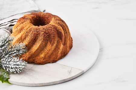 Vanilla and chocolate marble bundt cake on marble serving plate over white marble table with copy space for text.の写真素材