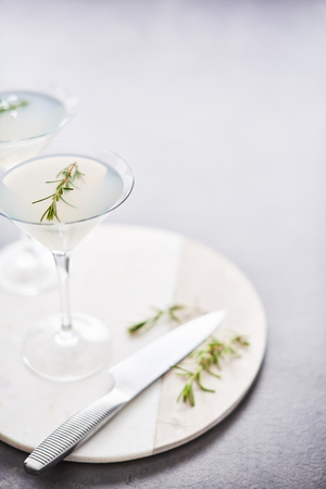 Summer drink. Refreshing summer alcoholic cocktail with rosemary or sparkling gin and lemonade on marble serving plate over dark concrete table. Copy space for text. Selective focus.の写真素材