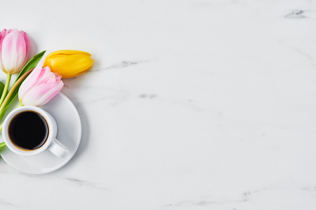 Cup of coffee with tulips on white marble table. Spring flowers. Top view. Copy space for text. Spring concept.の写真素材