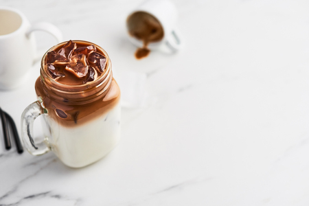 Ice coffee with milk in mason jar and black metal drinking straws on white marble table over white background. Top view. Copy space for text.の写真素材