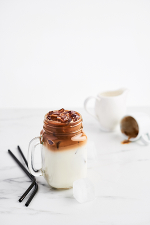 Ice coffee with milk in mason jar and black metal drinking straws on white marble table over white background. Copy space for text.の写真素材