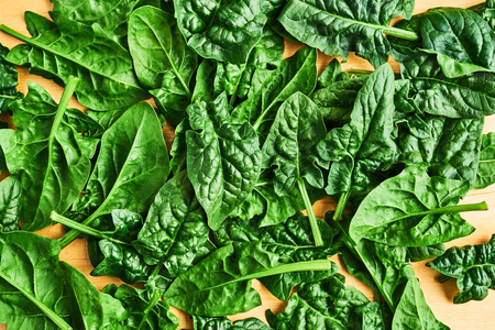 Fresh spinach leaves unwashed on wooden table. Spinach background. Top view with copy space for...