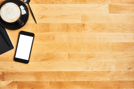 Cup of coffee or cappuccino with smartphone, notepad and pencil on yellow wooden table. Office concept. Top view. Copy space for text.の写真素材