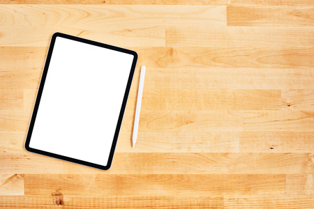 Digital tablet with blank white screen and pen on wooden office desk. Top view. Copy space for text or design. Flat lay.の写真素材