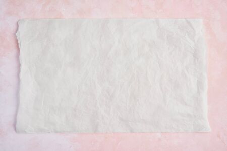 Crumpled piece of white parchment or baking paper on rose and white texture pattern background. Top view. Copy space for text and design element.の写真素材