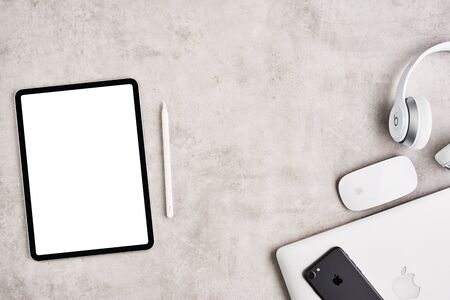 ZAGREB, CROATIA - SEPTEMBER 10, 2019: Top view on workplace. Apple iPad Pro, iPhone, MacBook Pro and Beats headphone on grey concrete background. Flat lay.のeditorial素材