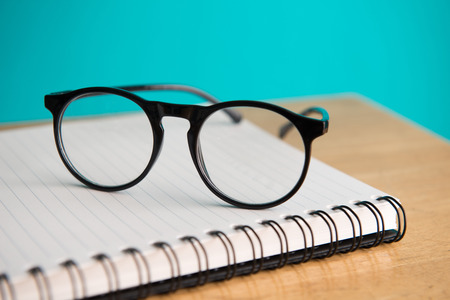 Eye glasses, blank notepad, and mechanical pencil on the table の写真素材