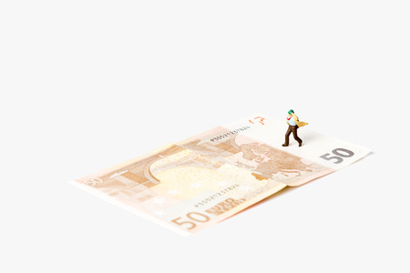 businessman figurine running on a euro banknote,on white background with clipping pathの写真素材