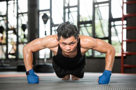 Attractive muscular man doing push-ups on gym floorの写真素材