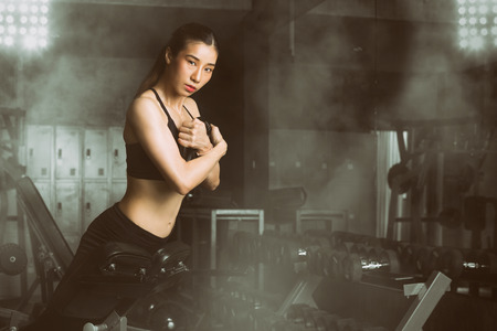 Toned picture,Fitness woman, Asian woman doing abdominal exercise at fitness center. Woman athlete doing situps at the gym holding heavy weight.の写真素材