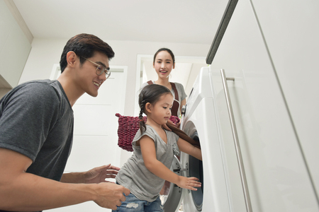 Happy Family loading clothes into washing machine in homeの写真素材