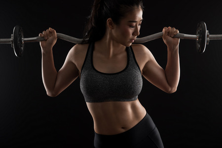 Beautiful girl exercising squatting with barbell,sport, fitness, bodybuilding on black,healthy and...