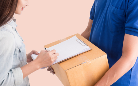 Delivery man giving a cardboard box to young womanの写真素材