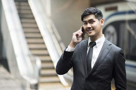Businessman smiling and talking on phone at subway.の写真素材