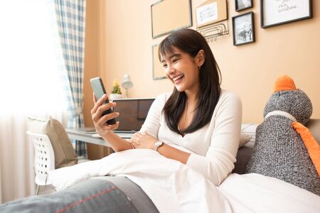 Young Asian woman works from home on computer Labtop, enjoys morning weekend, work from home...