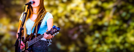 Young woman playing guitar on stage, close-up. Selective focus.の写真素材