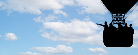 Silhouette of a man in a hot air balloon pointing at something. against a blue sky. Photography copy spaceの写真素材