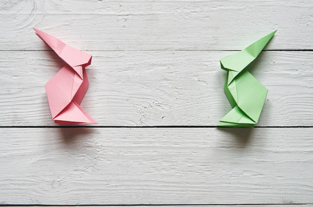 Paper origami handmade pink, green bunnies on white planks barn wood boards backgroundの写真素材