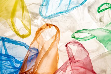 Empty wrinkled used backlit colorful plastic bags pattern on white background isolated. Environment...