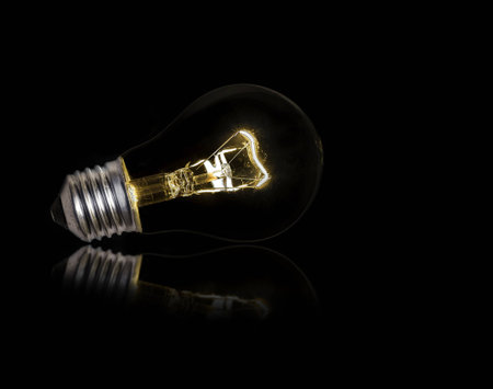 Light bulb lit on black backgroundの写真素材