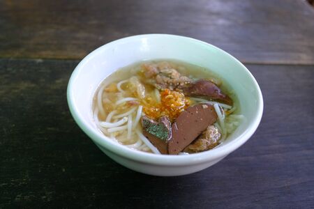 Mini bowl of steam Thai rice vermicelli with pig blood in clear soup topped with fried garlic on the...