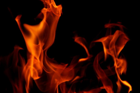 Closeup of a large fire. Wooden planks to the fire. The fire is lit in the night.