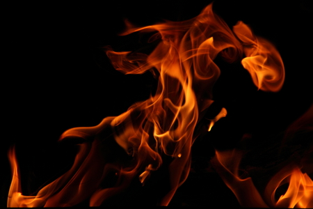 Closeup of a large fire. Wooden planks to the fire. The fire is lit in the night.