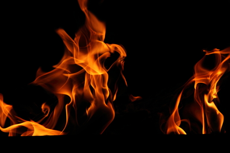 Closeup of a large fire. Wooden planks to the fire. The fire is lit in the night.