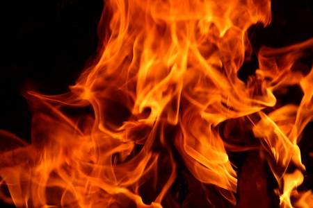 Closeup of a large fire. Wooden planks to the fire. The fire is lit in the night.
