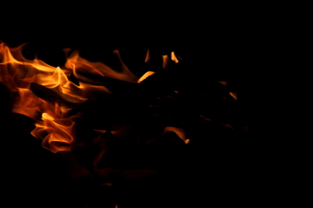 Closeup of a large fire. Wooden planks to the fire. The fire is lit in the night.