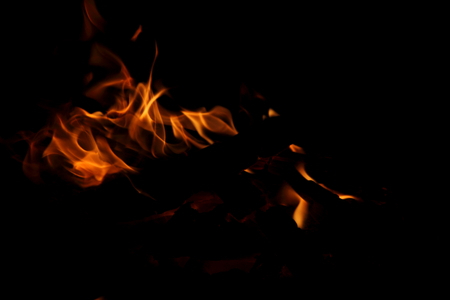 Closeup of a large fire. Wooden planks to the fire. The fire is lit in the night.